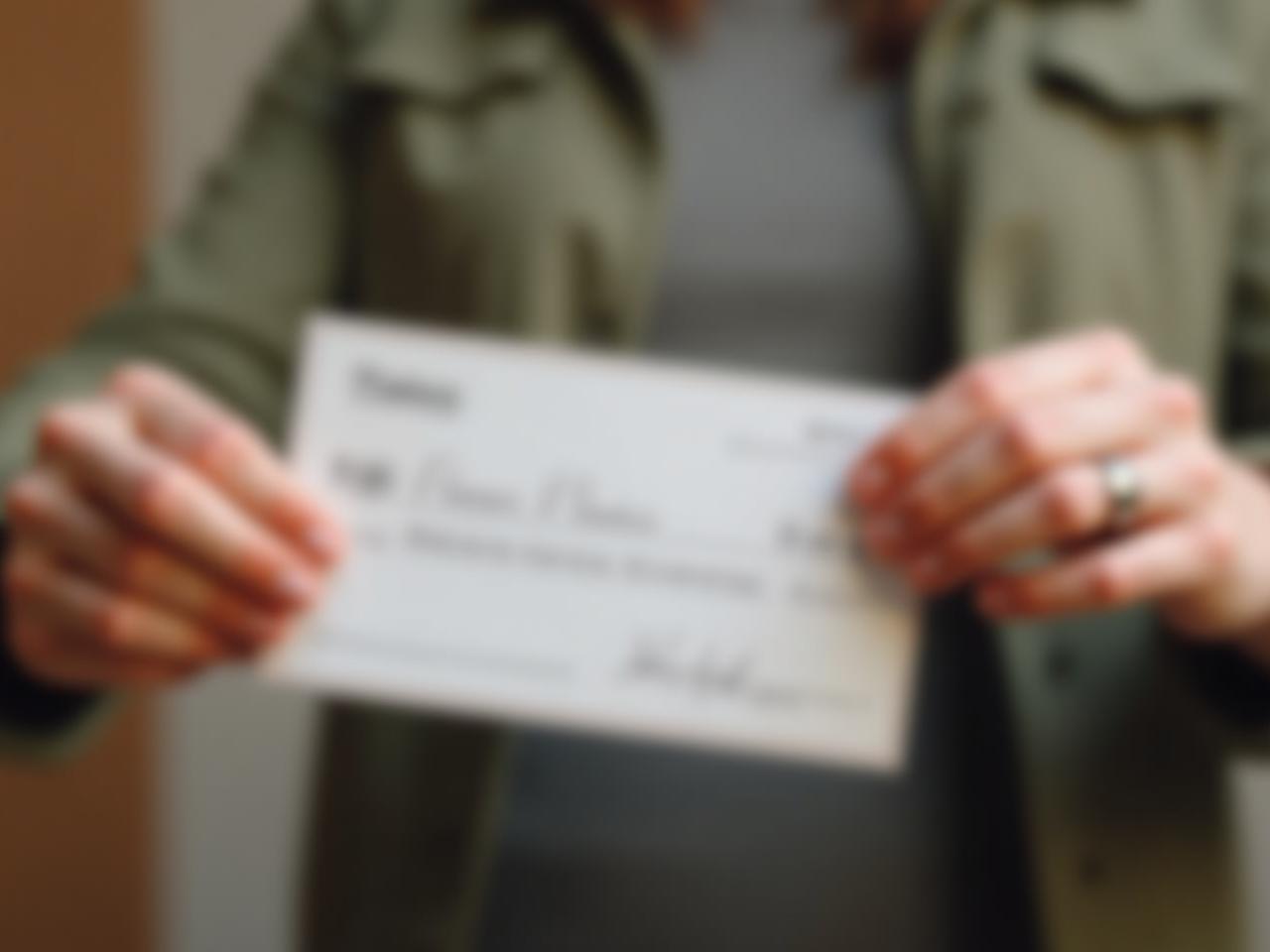 A person handing over a check with a warm smile, symbolizing the transformative power of giving.